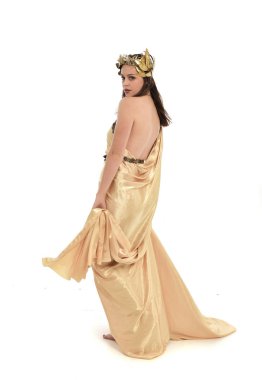 Tam boy poz ayakta altın Yunan elbisesi giymiş esmer kadın portresi. beyaz stüdyo arka plan üzerinde izole.