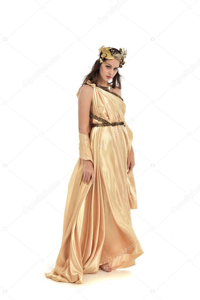 full length portrait of brunette woman wearing gold grecian gown, standing pose. isolated on white studio background.