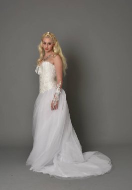 tam uzunlukta portre sarışın kız beyaz korse elbisesi giyiyor. gri studio arka plan üzerinde ayakta poz.