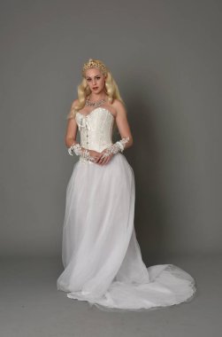 tam uzunlukta portre sarışın kız beyaz korse elbisesi giyiyor. gri studio arka plan üzerinde ayakta poz.