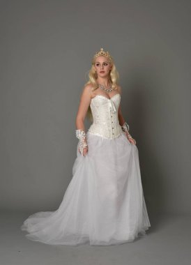 tam uzunlukta portre sarışın kız beyaz korse elbisesi giyiyor. gri studio arka plan üzerinde ayakta poz.