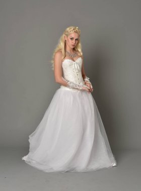 tam uzunlukta portre sarışın kız beyaz korse elbisesi giyiyor. gri studio arka plan üzerinde ayakta poz.