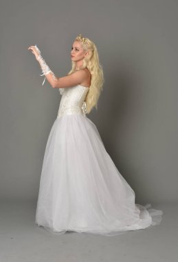 tam uzunlukta portre sarışın kız beyaz korse elbisesi giyiyor. gri studio arka plan üzerinde ayakta poz.