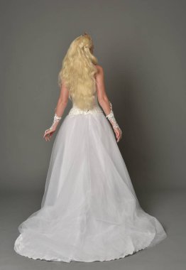 tam uzunlukta portre sarışın kız beyaz cüppe, kameranın arka ayakta pozuyla giyiyor. gri studio arka plan.