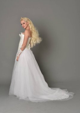 tam uzunlukta portre sarışın kız beyaz cüppe, kameranın arka ayakta pozuyla giyiyor. gri studio arka plan.