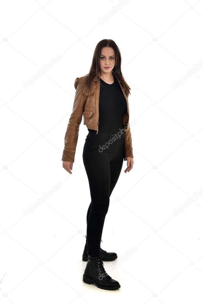 full length portrait of brunette girl wearing brown leather jacket. side profile, standing pose on white background.