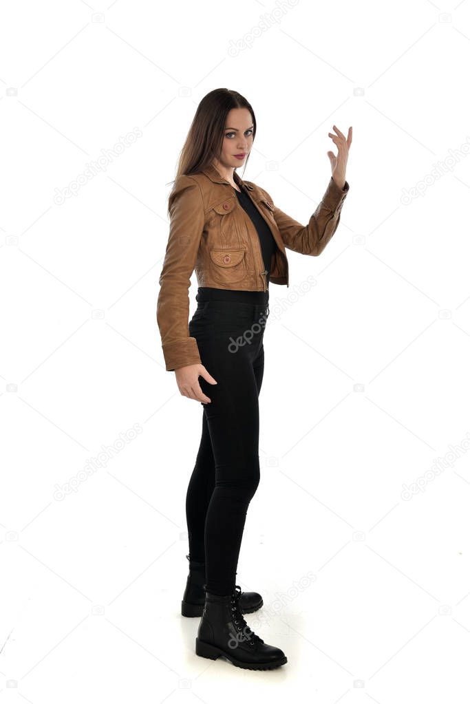 full length portrait of brunette girl wearing brown leather jacket. side profile, standing pose on white background.