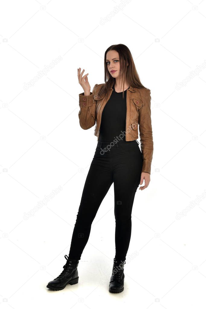 full length portrait of brunette girl wearing brown leather jacket.   standing pose on white background.
