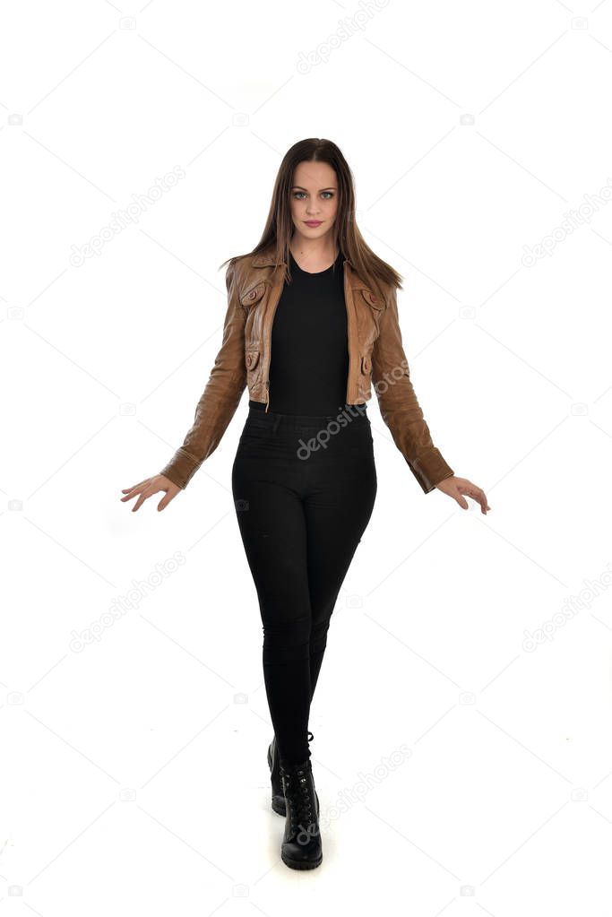 full length portrait of brunette girl wearing brown leather jacket.   standing pose on white background.