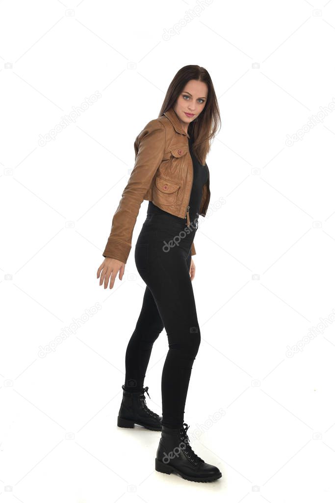 full length portrait of brunette girl wearing brown leather jacket.   standing pose on white background.