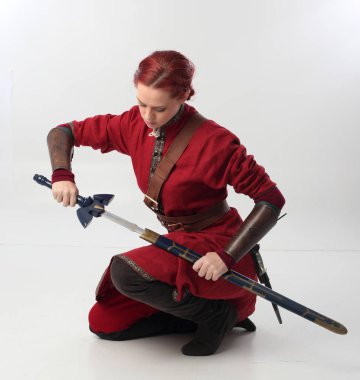 Kırmızı saçlı kız fantezi Ortaçağ giyinen, stüdyo arka plan üzerinde oturmuş poz tam uzunlukta portresi.