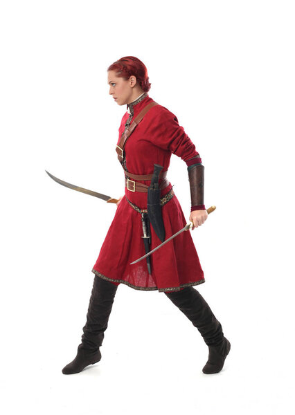 full length portrait of red haired girl wearing fantasy medieval costume, standing pose on studio background.