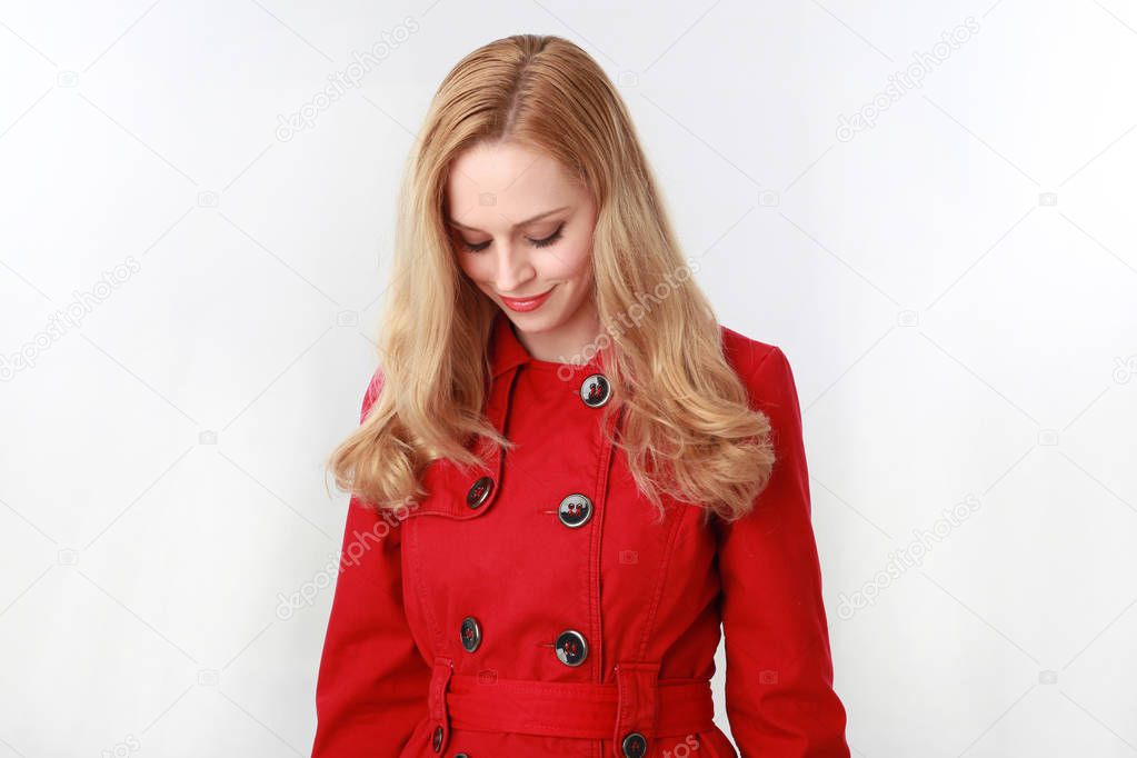 portrait of pretty blonde girl wearing red trench coat. isolated on white studio background.