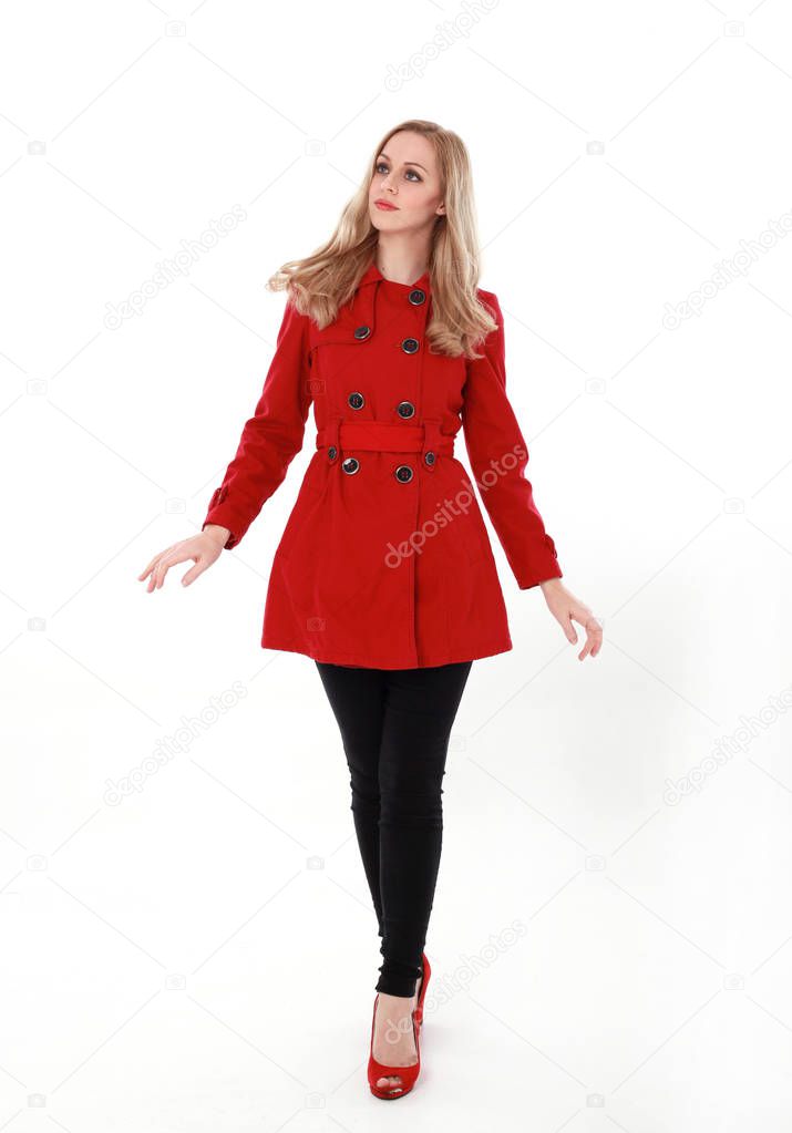 portrait of pretty blonde girl wearing red trench coat, full length standing pose.. isolated on white studio background.