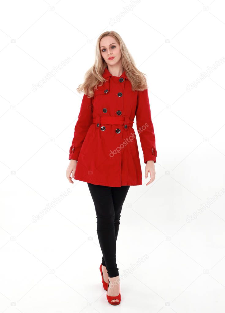portrait of pretty blonde girl wearing red trench coat, full length standing pose.. isolated on white studio background.