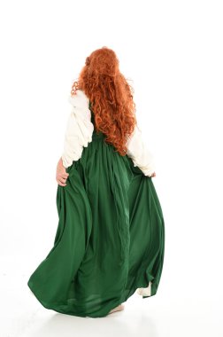 tam uzunlukta yeşil Ortaçağ elbisesi giymiş kırmızı saçlı kız portresi. beyaz stüdyo arka plan üzerinde ayakta poz.