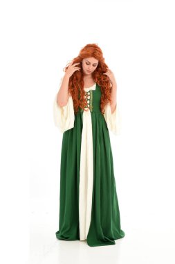 poz ayakta yeşil Ortaçağ elbisesi, tam uzunlukta kırmızı saçlı kız giyiyor. beyaz stüdyo arka plan üzerinde izole.