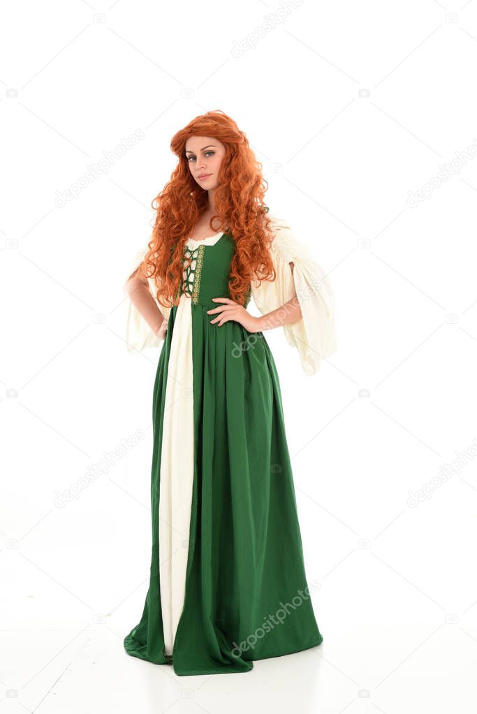 full length portrait red haired girl wearing green medieval gown, standing pose. isolated on white studio background.