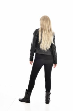 tam uzunlukta portre sarışın kız siyah deri giysiler giyiyor. ayakta poz geri gönderin. beyaz stüdyo arka plan üzerinde izole.