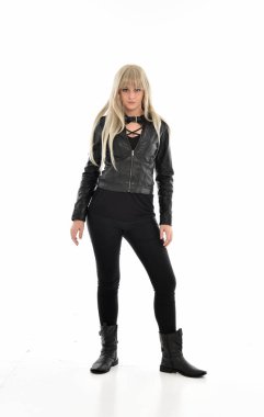 tam uzunlukta portre sarışın kız siyah deri elbiseler giymiş poz ayakta. beyaz stüdyo arka plan üzerinde izole.