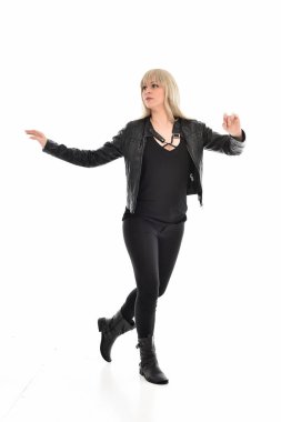 tam uzunlukta portre sarışın kız siyah deri elbiseler giymiş poz ayakta. beyaz stüdyo arka plan üzerinde izole.