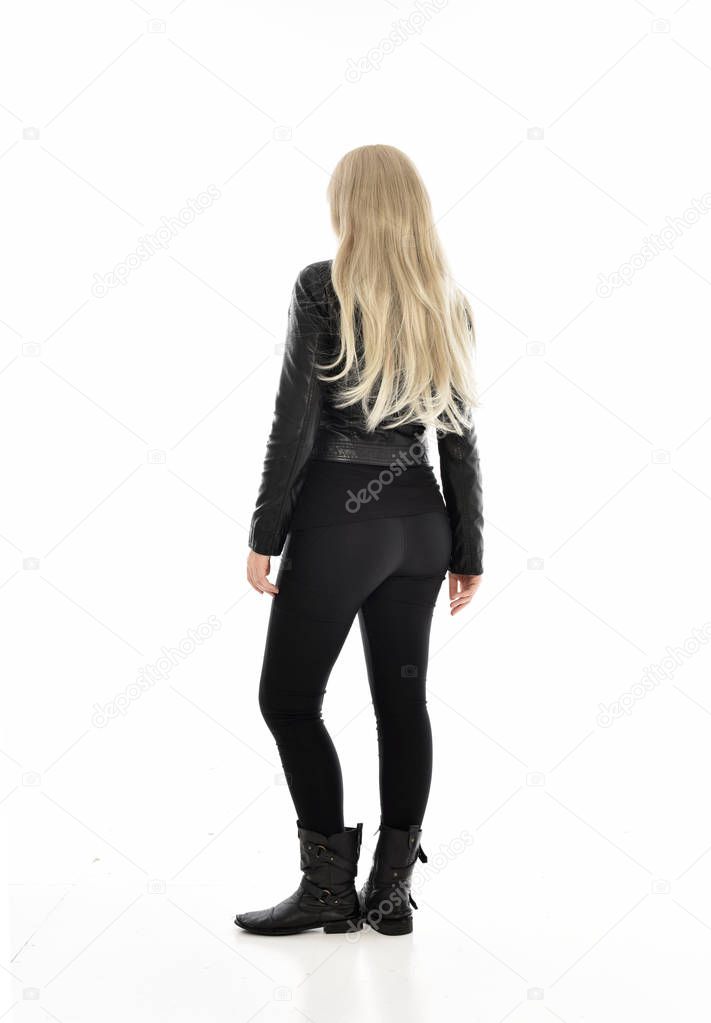 full length portrait blonde girl wearing black leather clothes, standing pose. isolated on white studio background.
