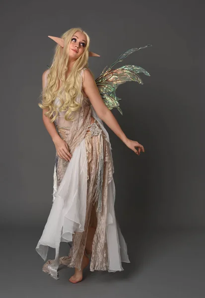full length portrait blonde girl wearing fantasy fairy costume, standing pose. grey studio background.