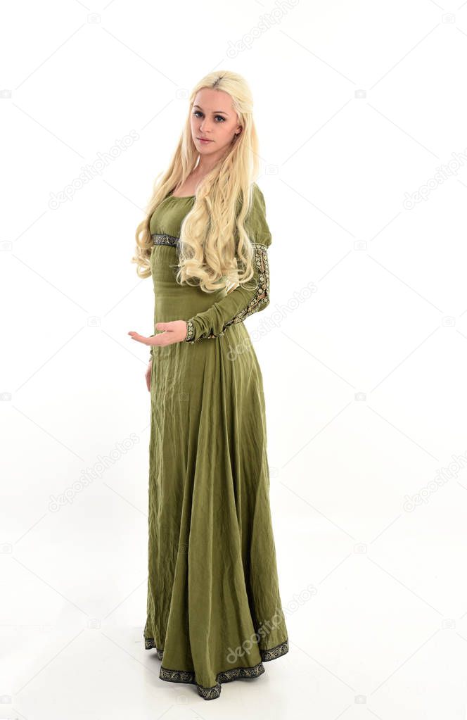 full length portrait of girl wearing green medieval gown, standing pose in side profile. isolated on white studio background.