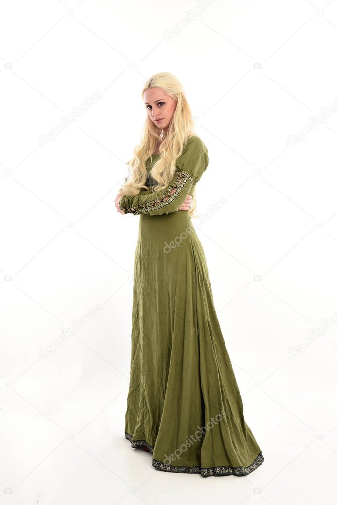 full length portrait of girl wearing green medieval gown, standing pose in side profile. isolated on white studio background.