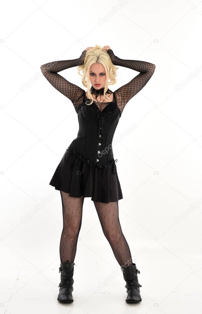 full length portrait of blonde girl wearing black gothic outfit, standing pose. isolated on white studio background.
