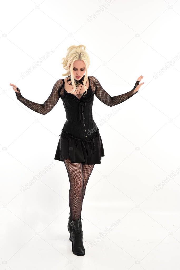 full length portrait of blonde girl wearing black gothic outfit, standing pose. isolated on white studio background.