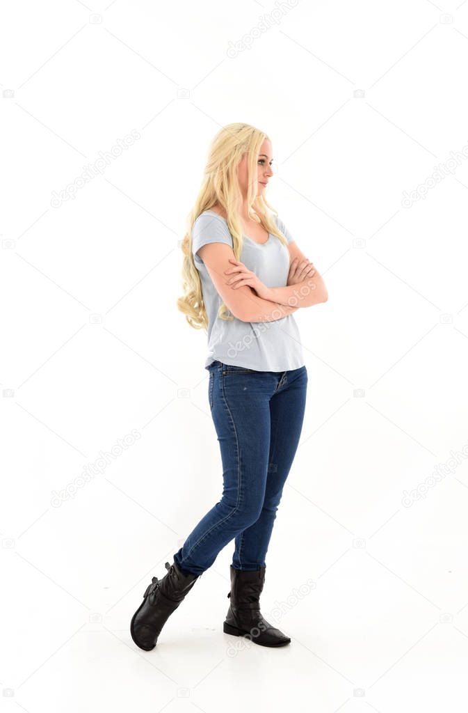 full length portrait of blonde girl wearing blue shirt and jeans, standing pose isolated on white studio background.