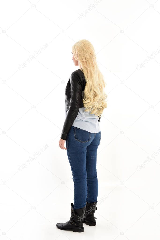 full length portrait of girl wearing simple jeans and leather jacket. standing pose, facing away from camera. isolated on white studio background.