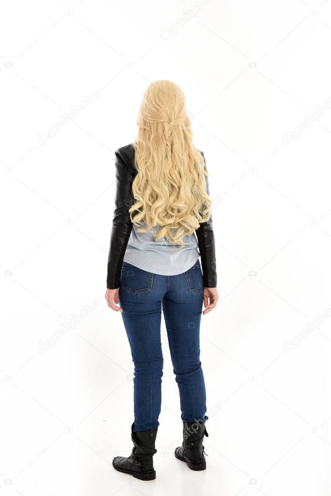 full length portrait of girl wearing simple jeans and leather jacket. standing pose, facing away from camera. isolated on white studio background.