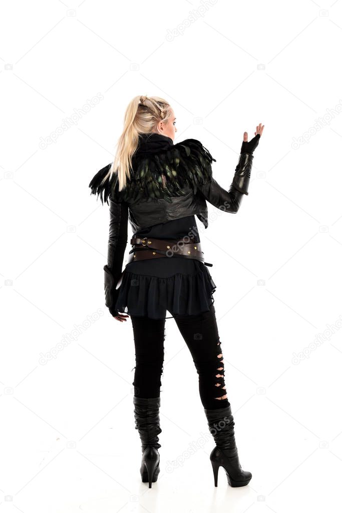 full length portrait of blonde girl wearing black torn gothic costume, standing pose with back to the camera. isolated on white studio background.