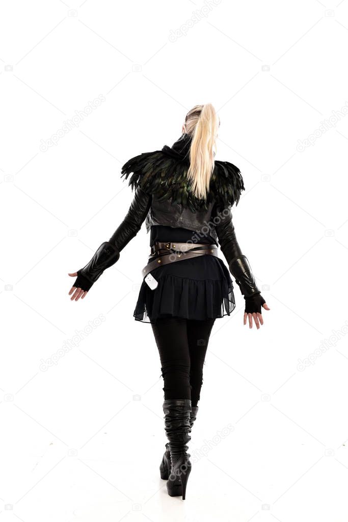 full length portrait of blonde girl wearing torn black feather costume. standing pose with back to the camera, isolated on white background.