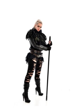 tam uzunlukta portre sarışın kız siyah yırtık kıyafeti giymiş bir personel'ın elinde. ayakta poz, beyaz stüdyo arka plan üzerinde izole.