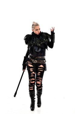tam uzunlukta portre sarışın kız siyah yırtık kıyafeti giymiş bir personel'ın elinde. ayakta poz, beyaz stüdyo arka plan üzerinde izole.