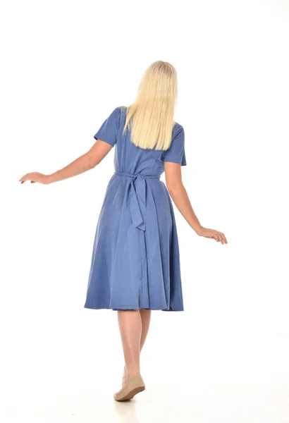 青いドレスを着ている金髪の女の子の完全な長さの肖像画 立ちポーズとカメラに戻る ホワイト スタジオの背景に分離 — ストック写真