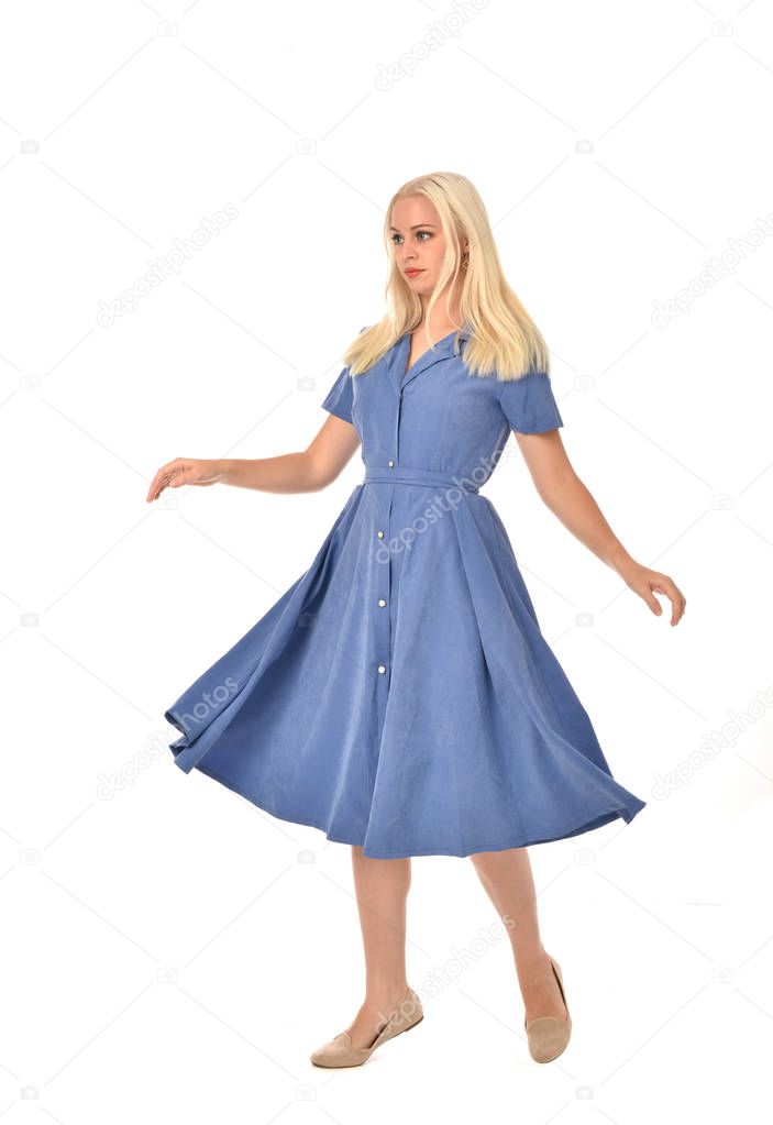 full length portrait of blonde girl wearing blue dress. standing pose. isolated on white  studio background.