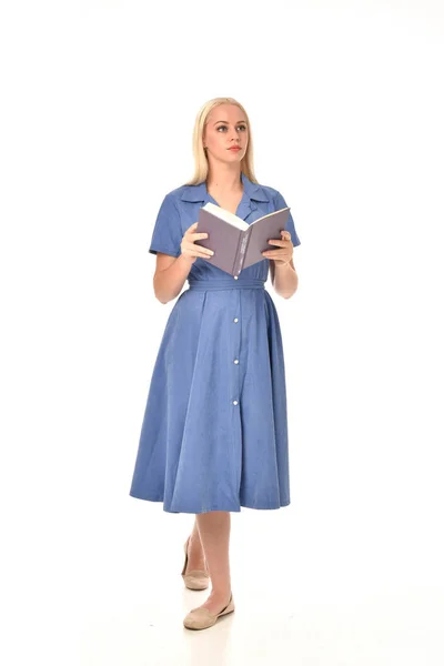 青いドレスを着ている金髪の女の子の完全な長さの肖像画 本を持って立ちポーズ ホワイト スタジオの背景に分離 — ストック写真