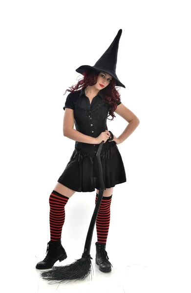 ほうきを持っている黒魔女衣装と先のとがった帽子を身に着けている赤髪少女の完全な長さの肖像画 立ちポーズ 白いスタジオ背景に分離 ストック写真 C Faestock ほうきを持っている黒魔女衣装と先のとがった帽子を身に着けている赤髪少女の完全な長さの肖像画 立ちポーズ 白いスタジオ背景に分離 ストック写真 C Faestock
