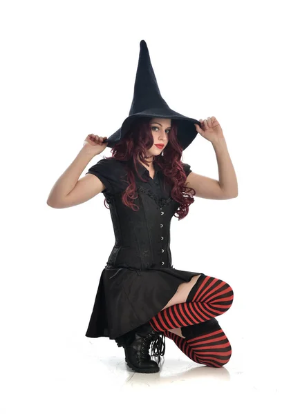 身穿黑色女巫服装和尖帽的红头发女孩全长肖像 在白色演播室背景被隔绝 — 图库照片