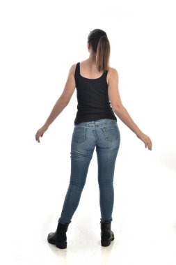 Tam boy siyah tek ve kot giyen esmer kız portresi. geri kamera için ayakta poz. beyaz stüdyo arka plan üzerinde izole.