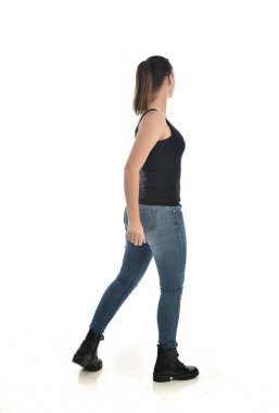 Tam boy siyah tek ve kot giyen esmer kız portresi. geri kamera için ayakta poz. beyaz stüdyo arka plan üzerinde izole.