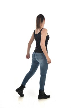 Tam boy siyah tek ve kot giyen esmer kız portresi. geri kamera için ayakta poz. beyaz stüdyo arka plan üzerinde izole.