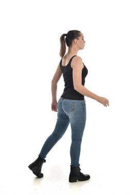 Tam boy siyah tek ve kot giyen esmer kız portresi. geri kamera için ayakta poz. beyaz stüdyo arka plan üzerinde izole.