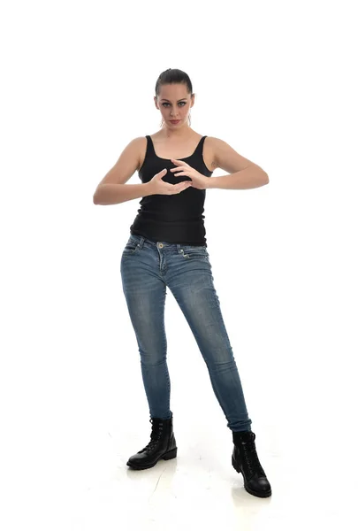 黒シングルとジーンズを身に着けているブルネットの女の子の完全な長さの肖像画 ポーズを立っています ホワイト スタジオの背景に分離 — ストック写真