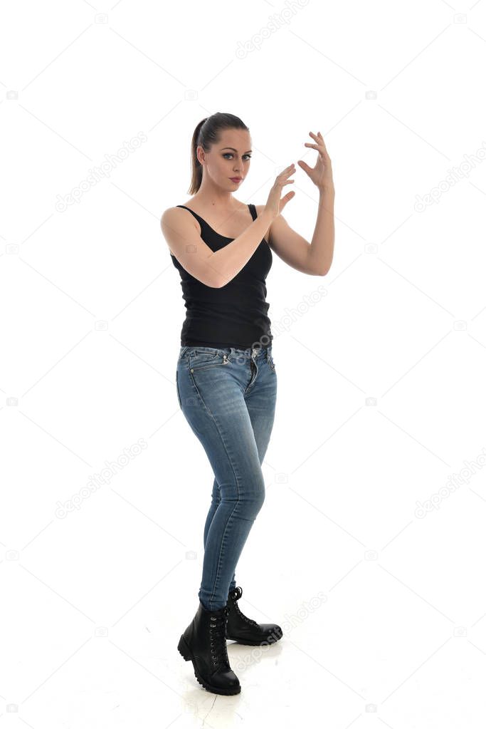 full length portrait of brunette girl wearing black single and jeans. standing pose. isolated on white studio background.