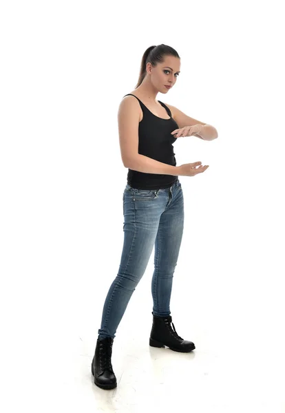 黒シングルとジーンズを身に着けているブルネットの女の子の完全な長さの肖像画 ポーズを立っています ホワイト スタジオの背景に分離 — ストック写真
